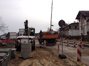Blick auf Fahrstraße mit LKW und Bagger, heute Foto von Bagger und LKW u. a. auf der Einmündung am Kino - heute.