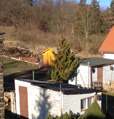 Foto von Gartenbereich mit Buden und Bauschutt ist zu sehen.