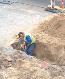 Foto von einem Bauarbeiter, der etwas mit einer Trennscheibe durchtrennt.