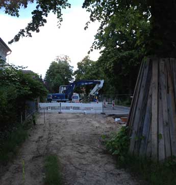 Foto von dem blauen Bagger, der vor dem Grundstück Nr. 131 steht, wo das neue Haus entsteht. Das auf einem 