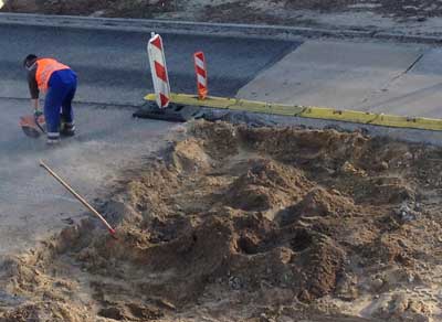 Foto von einem Bauarbeiter, der ein Stück Straßenbeton herausschneidet.