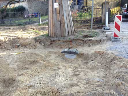 Foto von einem Schacht inaufgewühltem Sand vor einem Baum.