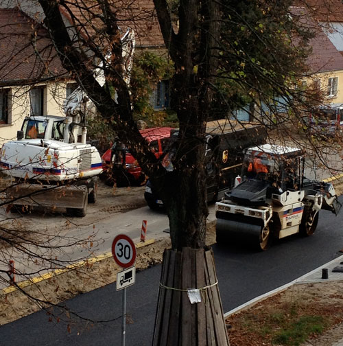 Foto von der Baustraße vor dem Haus mit Bagger und Walze und PkW's - heute Mittag um 14 Uhr.