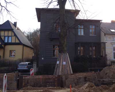 Foto: Straßenbaustelle mit Haus im Hintergrund