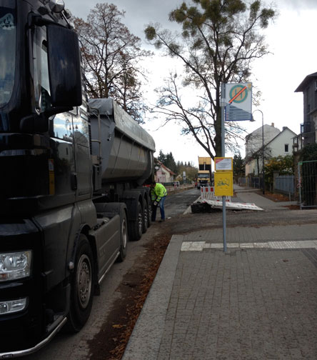 Blick auf Fahrstraße mit LKW vor Hausnr. 132, heute Foto von LKW mit Asphalt und auf der neuen Fahrbahn.