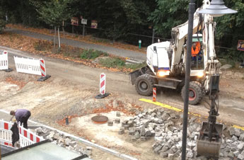 Blick auf Bagger und Pflasterer heute Foto von einem Bagger, der Steine sortiert und einem Pflasterer ist zu sehen.