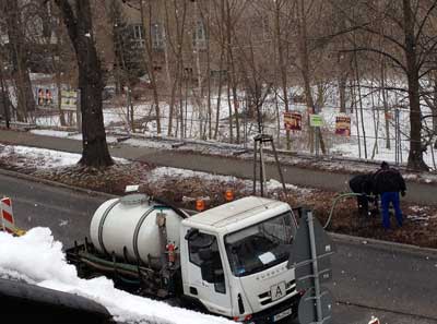 Gyllyspülung Tankauto und zwei Männer, die den Gully spülen ist zu sehen