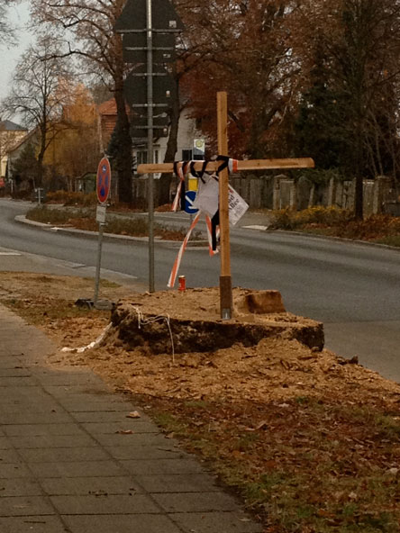 Foto von Baumstumpf mit Holzkreuz der dicken Linde Nr. 109 mit Kerze in der Eisenbahnstraße.