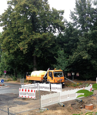 Foto von einem LKW, der mit Schlauch Pflanzen wässert - heute.