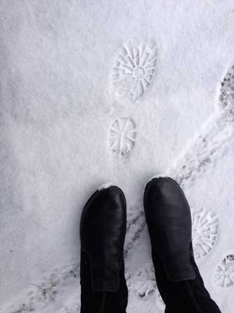 Foto von einem Schuhabdruck im Schnee und ein paar Schuhen